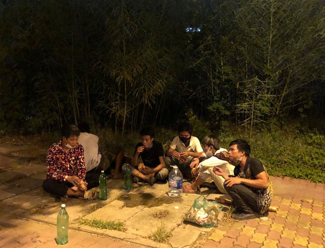 Nhóm phụ hồ ngồi nghỉ chân bên vệ đường Phạm Hùng, ăn mì tôm sống, uống nước lọc trên đường đi bộ về quê. (Ảnh: PV/Vietnam+) Gỡ khó trong hỗ trợ những mảnh đời 'mắc kẹt' lại đô thị trong đại dịch ảnh 2