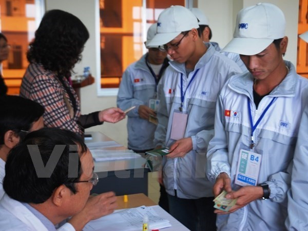 Lao động làm thủ tục trước khi đi làm việc ở nước ngoài. (Ảnh: PV/Vietnam+) Thu hồi giấy phép, xử phạt hàng loạt doanh nghiệp xuất khẩu lao động ảnh 1