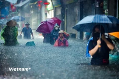 Người dân Thủ đô bì bõm lội nước dưới cơn mưa cực lớn trong ngày 30/9/2025. (Ảnh: Hoài Nam/Vietnam+)