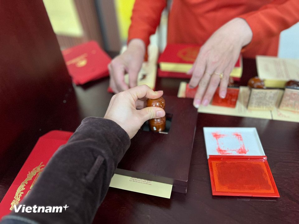 Tự tay in ấn triện lên tấm thiệp Xuân. (Ảnh: Mai Mai/Vietnam+)