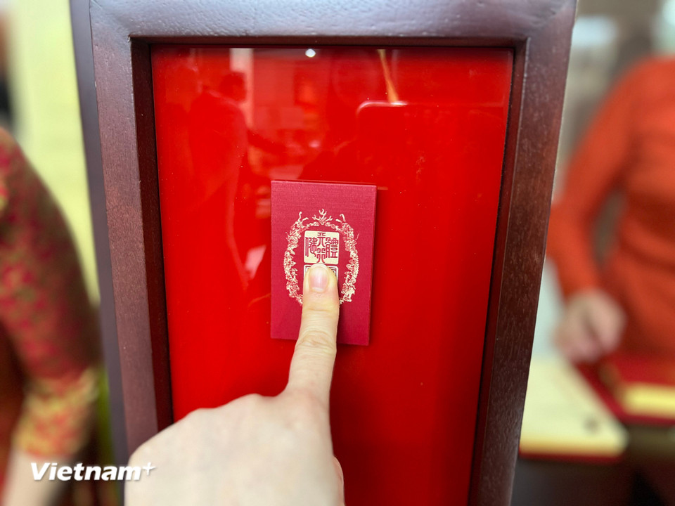 Công chúng trải nghiệm "bắt thăm" để in ấn triện lên các tấm thiệp Xuân và lưu giữ bản in ý nghĩa làm kỷ niệm. (Ảnh: Mai Mai/Vietnam+)