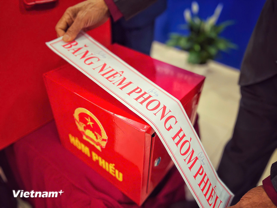 Các thành viên Tổ bầu cử dán băng niêm phong hòm phiếu sau khi kiểm tra hòm trống. (Ảnh: Mai Mai/Vietnam+)
