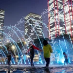 Trẻ em vui chơi dưới đài phun nước dọc sông Hàn ở Thủ đô Seoul (Hàn Quốc). (Ảnh: Yonhap/TTXVN)