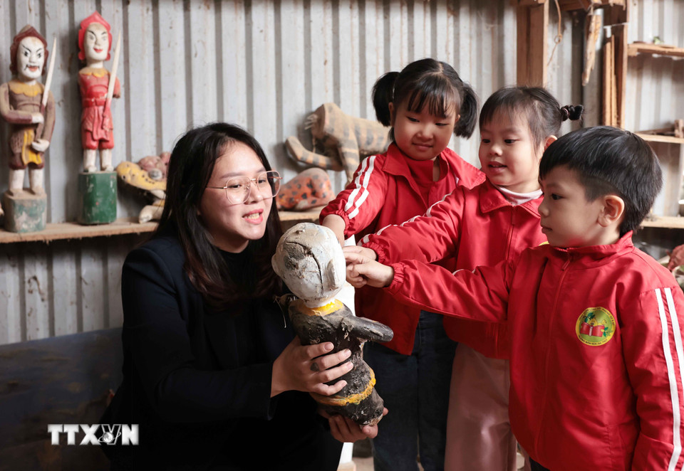 Trẻ nhỏ thích thú với những quân trò rối tại gia đình nghệ nhân Nguyễn Văn Phi khi được đến tham quan, trải nghiệm ở làng rối nước Đào Thục. (Ảnh: Trần Việt/TTXVN)