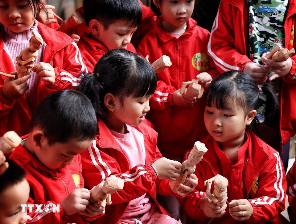 Trẻ nhỏ thích thú với những quân trò rối được chế tác tại gia đình nghệ nhân Nguyễn Văn Phi ở làng Đào Thục. (Ảnh: Phạm Hậu/TTXVN)