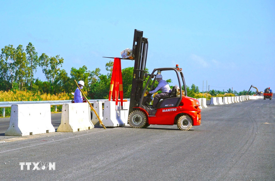 Các công nhân đang lắp dải phân cách, hoàn thiện những bước cuối để kịp thông xe kỹ thuật. (Ảnh: Huỳnh Anh/TTXVN)