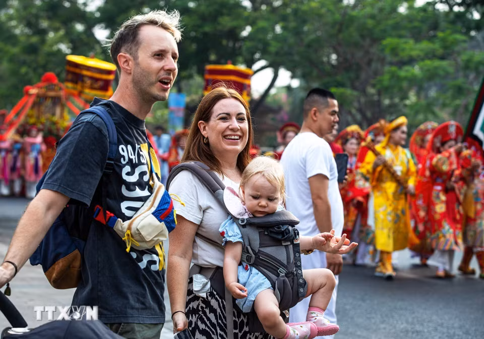 Du khách nước ngoài thích thú khi được chiêm ngưỡng đoàn rước Mẫu đầy màu sắc trên phố. (Ảnh: Vân Chi/TTXVN phát)