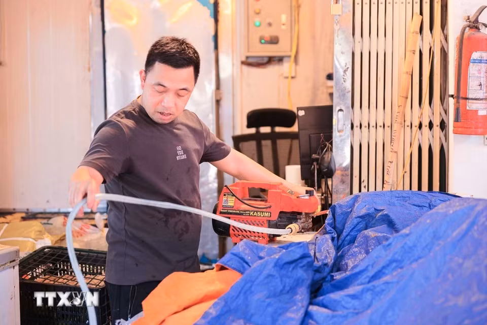 Anh Đàm Mạnh, tiểu thương tại Chợ Đồng Xuân, sử dụng máy phun sương để giảm nhiệt, chống chọi với thời tiết nắng nóng gay gắt khi nền nhiệt tăng cao. (Ảnh: Hoàng Hiếu/TTXVN)
