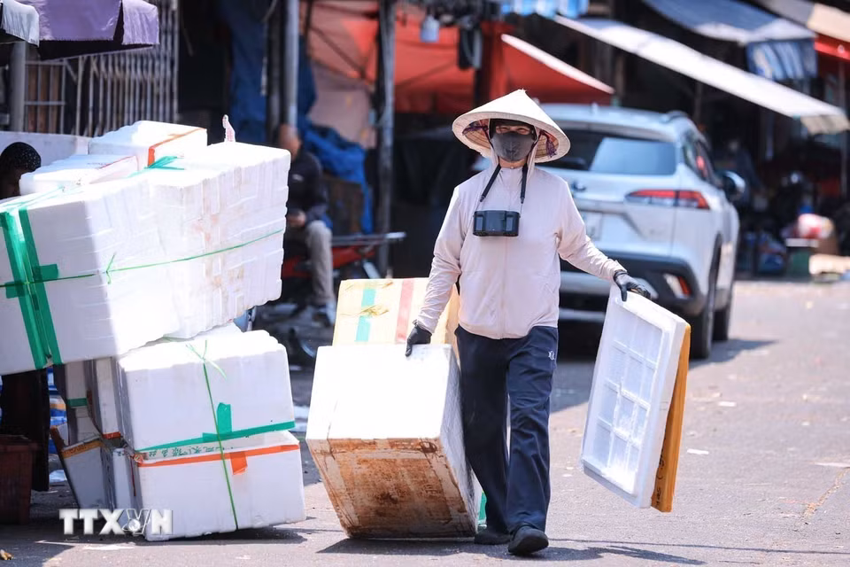 Người lao động mang theo quạt tích điện mini để giảm cái nóng do nhiệt độ ngoài trời tăng cao. (Ảnh: Hoàng Hiếu/TTXVN)