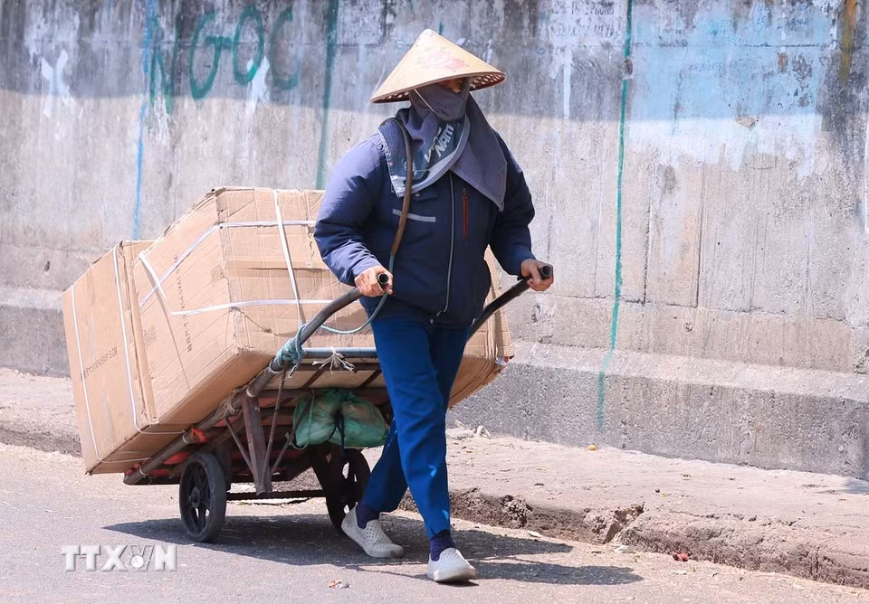 Nguời lao động tại chợ Đồng Xuân làm việc, di chuyển ngoài trời gặp nhiều khó khăn khi có lúc nền nhiệt đo được trên 50 độ C. (Ảnh: Hoàng Hiếu/TTXVN)