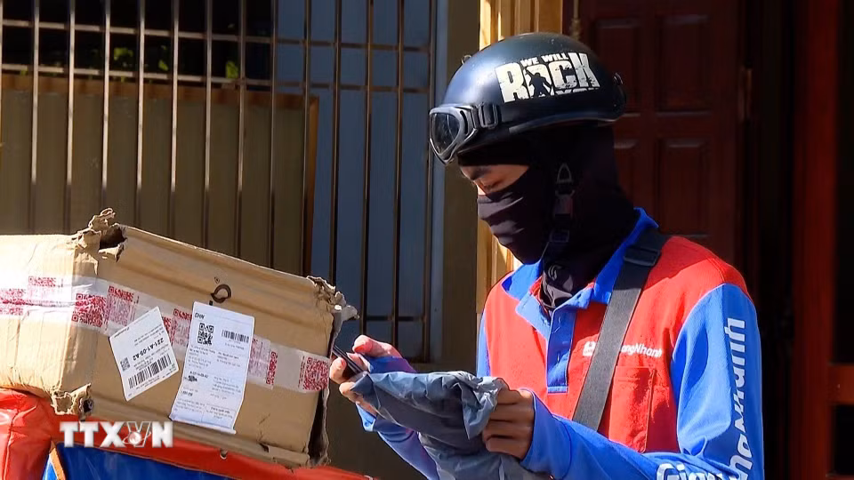 Anh Nguyễn Anh Đức,làm nghề shipper vẫn có mặt tại các tuyến phố để giao từng đơn hàng trong thời tiết oi bức, hầm hập hơi nóng. (Ảnh: Tuấn Anh/TTXVN)