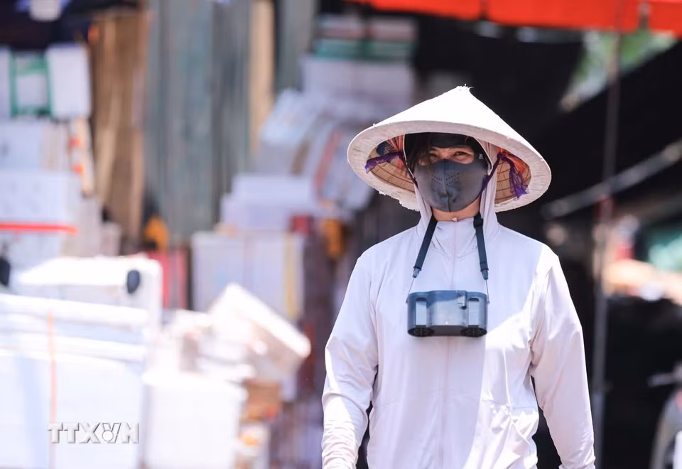 Người lao động mang theo quạt tích điện mini để giảm cái nóng do nhiệt độ ngoài trời tăng cao. (Ảnh: Hoàng Hiếu/TTXVN)