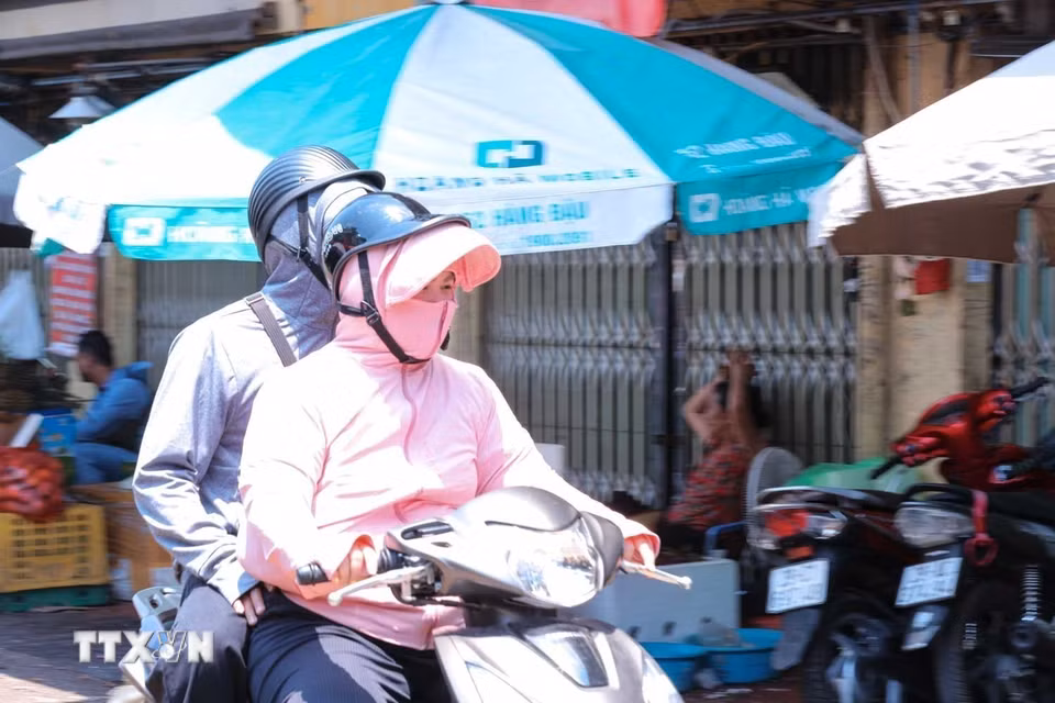 Nhiệt độ ngoài trời tăng cao, có lúc trên 50 độ C, khiến người dân di chuyển ngoài đường phải trang bị kín mít với áo chống nắng, khẩu trang, găng tay, mũ rộng vành. (Ảnh: Hoàng Hiếu/TTXVN) ​