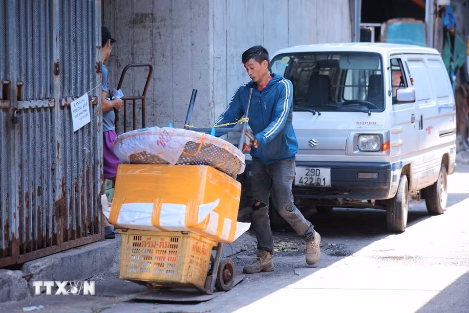 Thời tiết nắng nóng khiến việc lao động, di chuyển ngoài trời của người lao động chợ Đồng Xuân thêm gian nan. (Ảnh: Hoàng Hiếu/TTXVN)