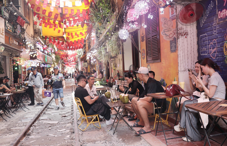 Du khách trải nghiệm và thưởng thức đồ uống tại những quán càphê sát đường ray tàu hỏa, sáng 15/6. (Ảnh: Thành Phương/TTXVN)