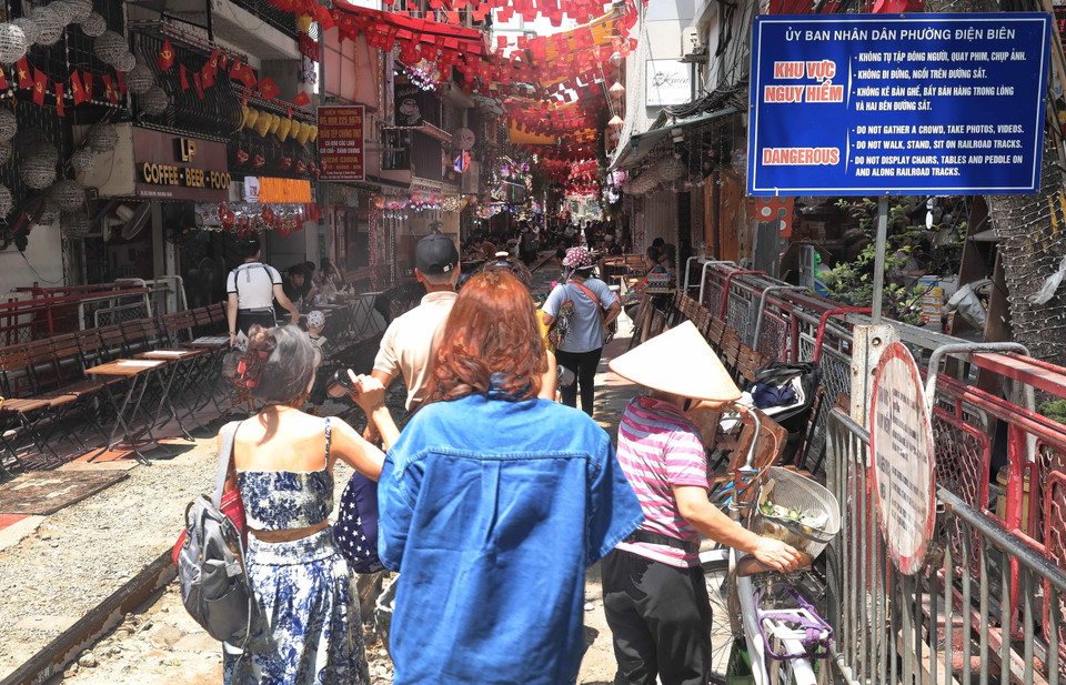 Du khách phớt lờ biển cảnh báo nguy hiểm khi đi lại trên tuyến đường sắt, sáng 15/6. (Ảnh: Thành Phương/TTXVN)