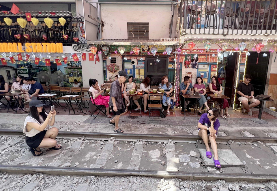 Nhiều du khách nước ngoài tranh thủ "check-in" tại "phố càphê đường tàu" ở Hà Nội, sáng 15/6. (Ảnh: Thành Phương/TTXVN)
