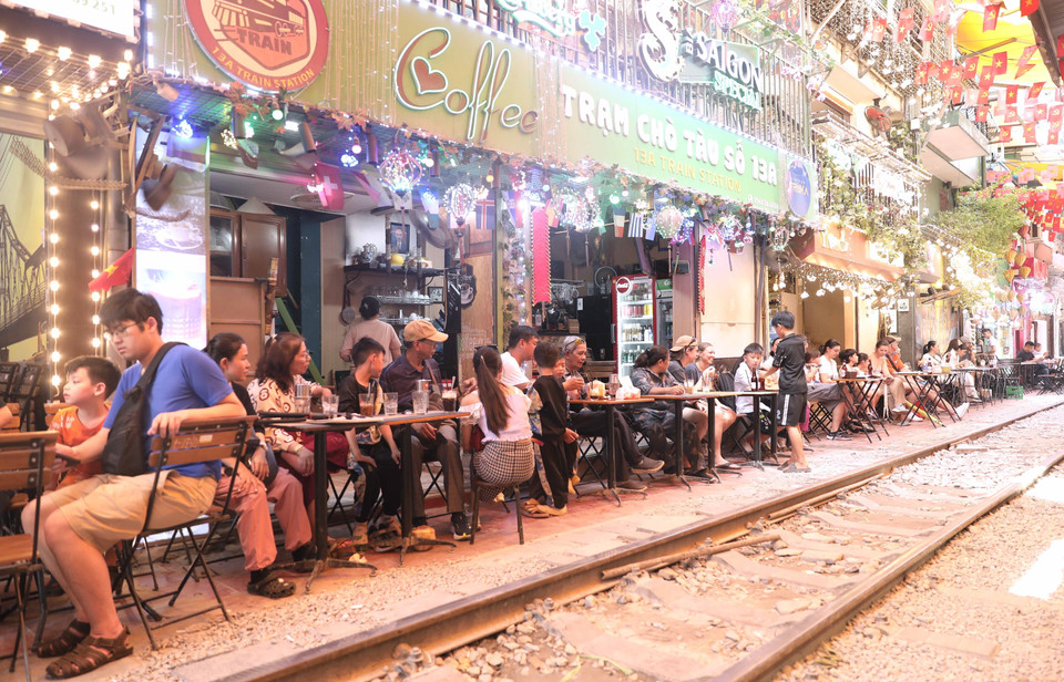 Du khách thư giãn, trải nghiệm không khí đặc trưng của quán càphê sát đường ray tàu hỏa. (Ảnh: Thành Phương/TTXVN)