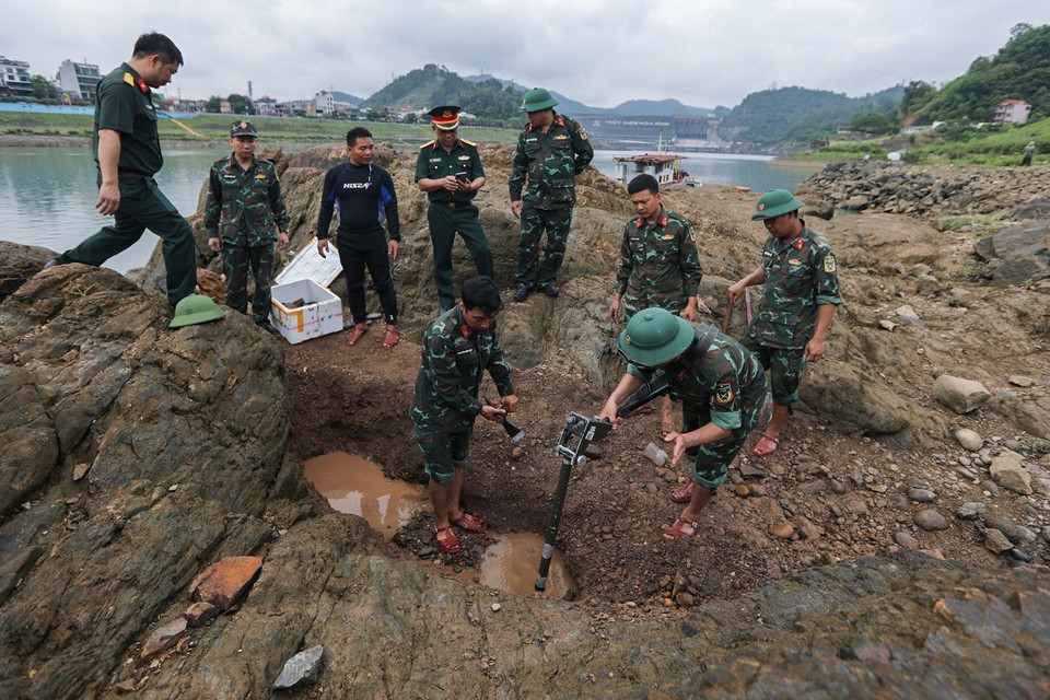Lực lượng làm nhiệm vụ rà phá bom mìn, vật nổ tại khu vực lòng sông Đà, nằm cách không xa khu vực giới hạn an toàn của Nhà máy Thủy điện Hòa Bình. (Ảnh: Trọng Đạt/TTXVN)