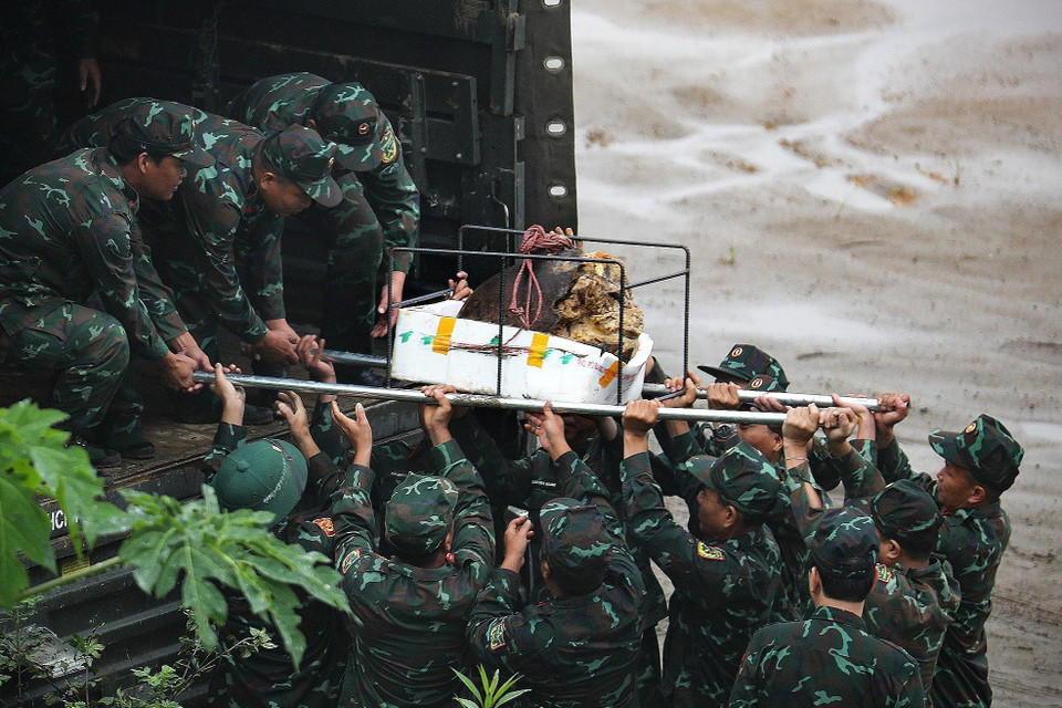 Cán bộ, chiến sỹ di chuyển đầu nổ quả bom có trọng lượng gần 1000kg lên xe để chuyển đi hủy nổ. (Ảnh: Trọng Đạt/TTXVN)