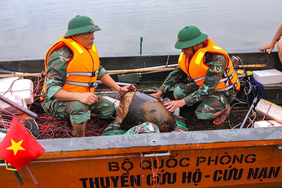 Phần nửa đầu quả bom có trọng lượng 2000 bảng Anh (gần 1 tấn) được các chiến sỹ đưa lên thuyền vận chuyển về nơi tập kết vật nổ. (Ảnh: Trọng Đạt/TTXVN)