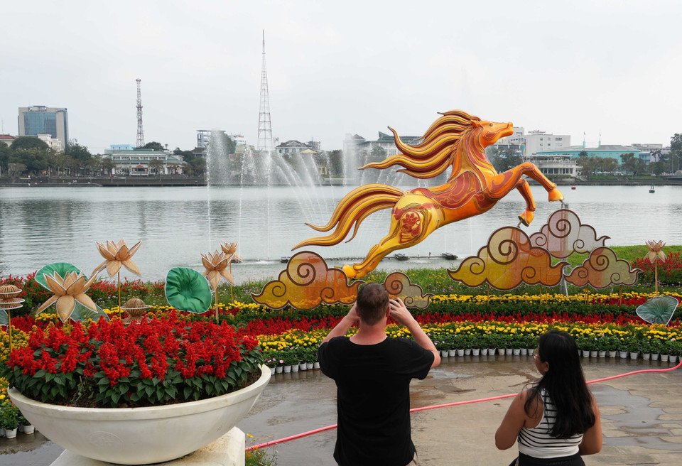 Du khách quốc tế tham quan linh vật ngựa đặt ở bờ Bắc sông Hương, thành phố Huế. (Ảnh: Nguyên Lý/TTXVN)