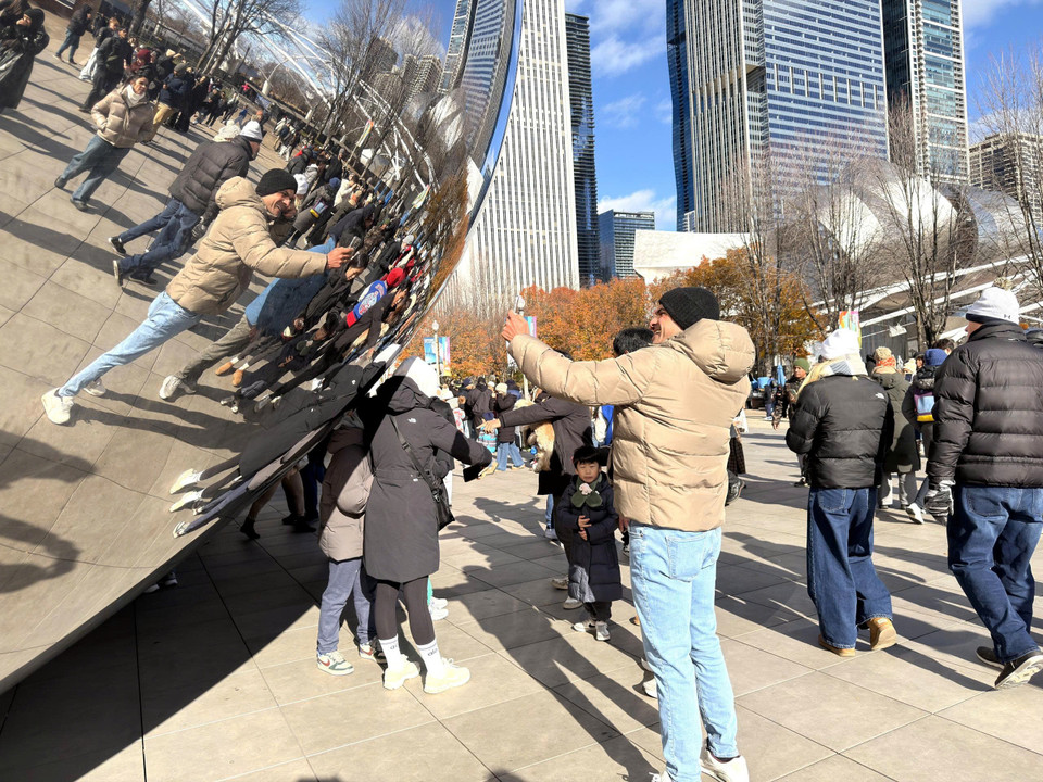 Du khách chụp ảnh phản chiếu của mình bên tác phẩm điêu khắc biểu tượng của thành phố Chicago. (Ảnh: Ngọc Quang/TTXVN)