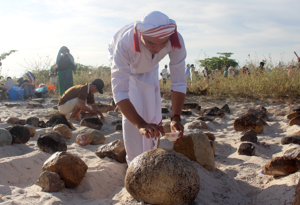 Nghi thức tẩy uế các phần mộ trước khi đọc kinh cúng. (Ảnh: Hồng Hiếu/TTXVN)
