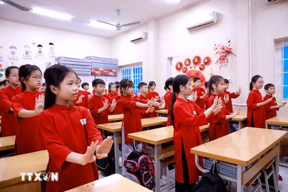 Trong tà áo dài đỏ rực rỡ, các học sinh say sưa thực hiện những động tác múa hát Xoan nhịp nhàng, góp phần tái hiện không gian văn hóa truyền thống ngay giữa lớp học. (Ảnh: Hoàng Hùng/TTXVN)