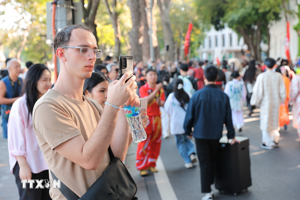 Du khách ngắm nhìn và lưu lại khoảnh khắc trong lễ diễu hành. (Ảnh: Phạm Tuấn Anh/TTXVN)