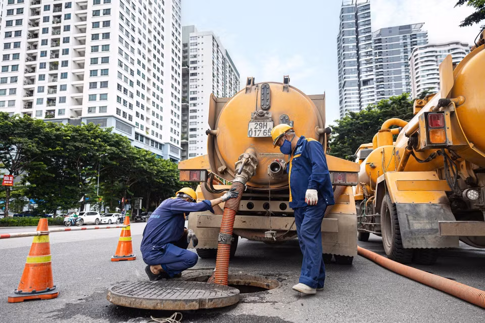 Công nhân trực tiếp xuống cống ngầm thu gom rác để vận chuyển về khu tập kết xử lý. (Ảnh: Tiến Long/TTXVN phát)