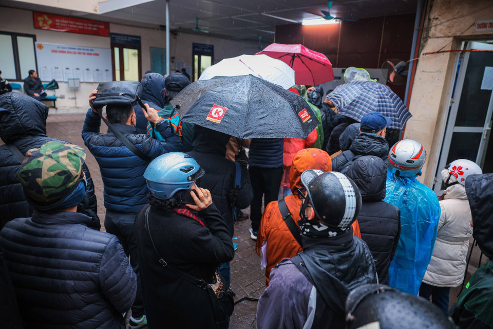 Người dân xếp hàng chờ đợi vào lấy số thứ tự khi trời đang mưa, rét. (Ảnh: Hoàng Hiếu/TTXVN)