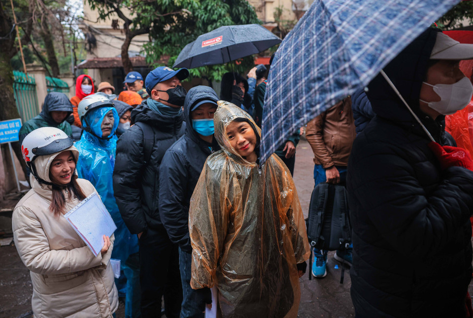 Người dân xếp hàng chờ đợi vào lấy số thứ tự khi trời đang mưa, rét. (Ảnh: Hoàng Hiếu/TTXVN)