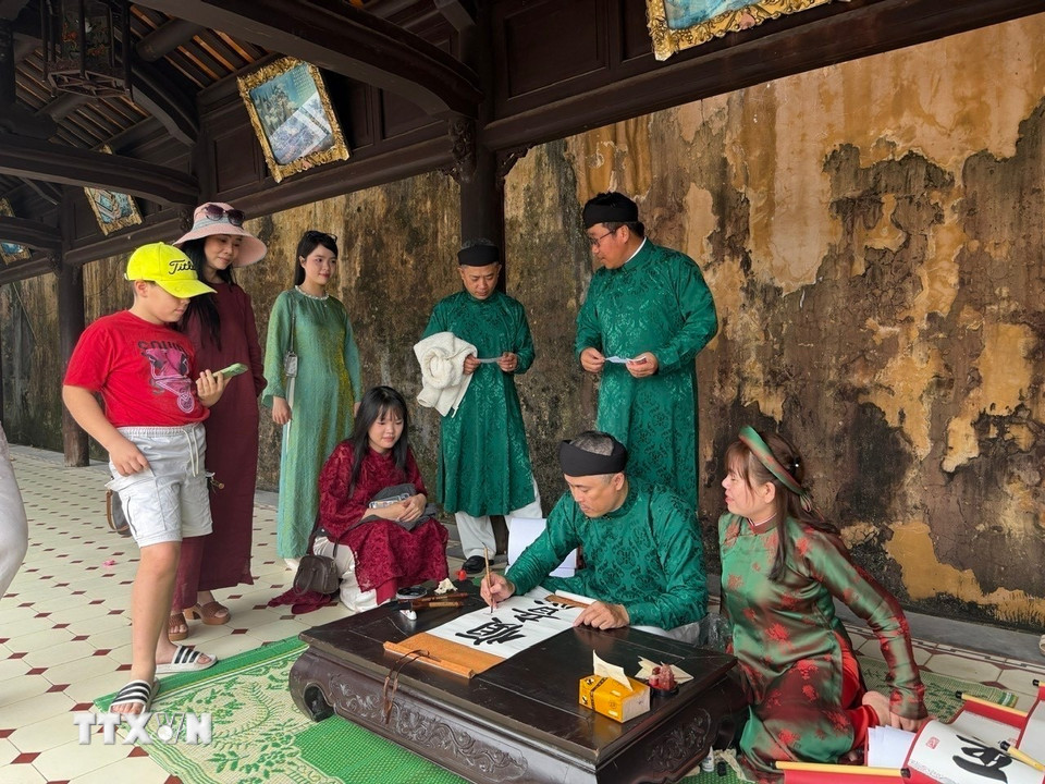 Trong ảnh: Nhiều du khách thích thú với tục xin chữ đầu năm tại Đại Nội Huế. (Ảnh: Hải Âu/TTXVN.)