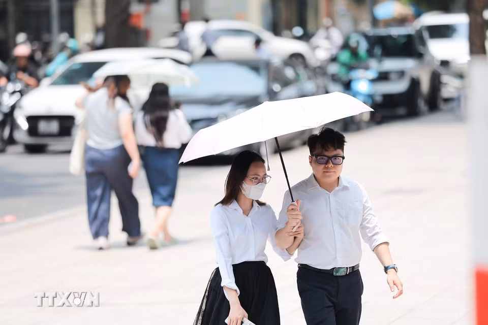 Người dân che ô khi di chuyển trên phố dưới trời nắng gay gắt. (Ảnh: Lê Đông/TTXVN)