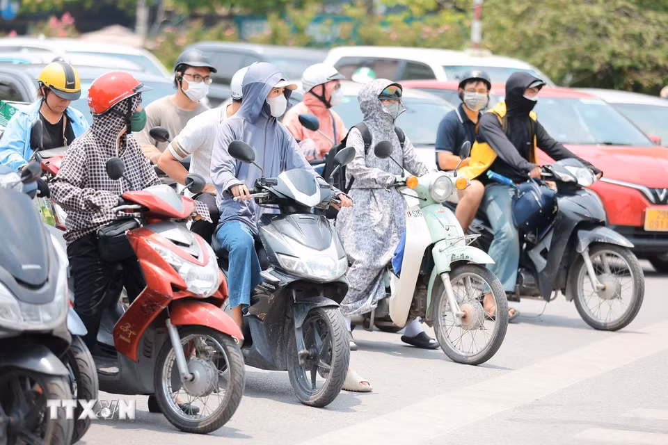 Khẩu trang, áo chống nắng là những thứ không thể thiếu của người dân khi tham gia giao thông. (Ảnh: Lê Đông/TTXVN)