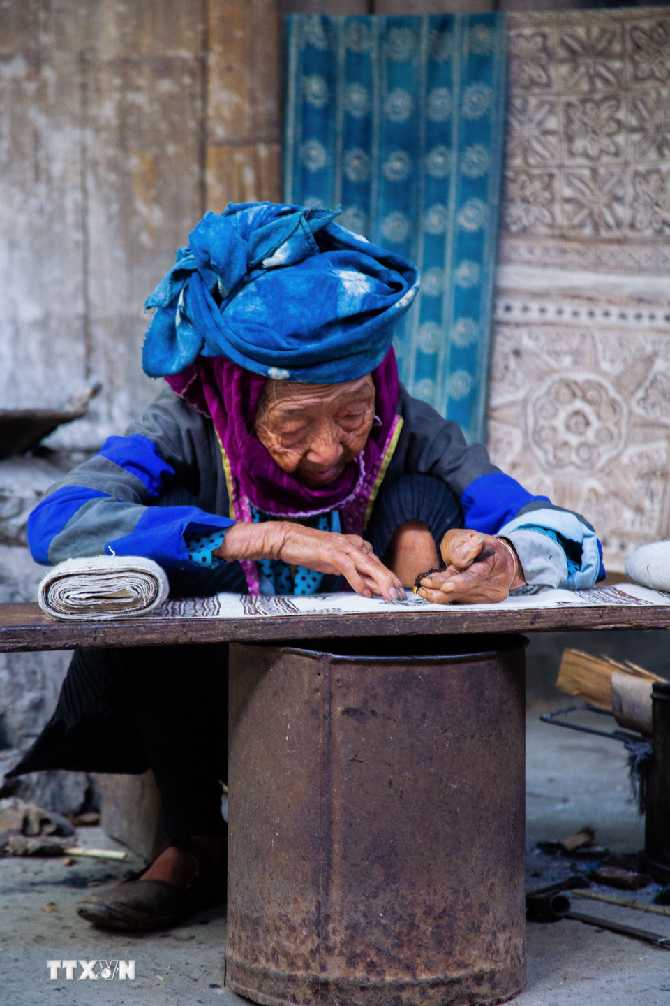 Tỉ mỉ vẽ hoa văn bằng sáp ong trên vải lanh, công đoạn đòi hỏi sự khéo léo và kinh nghiệm lâu năm. (Ảnh: Lan Anh/TTXVN phát)