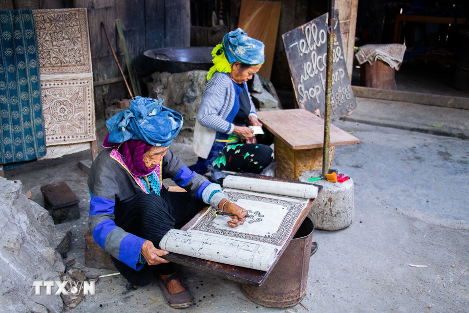 Người phụ nữ Mông tại Lùng Tám thực hiện công đoạn vẽ sáp ong lên vải lanh trước khi nhuộm chàm. (Ảnh: Lan Anh/TTXVN phát)