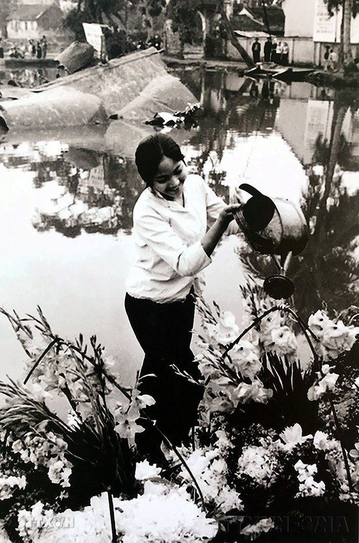 Hình ảnh cô gái tưới hoa bên xác chiếc máy bay Mỹ B-52 rơi ở hồ Hữu Tiệp, làng Ngọc Hà (Hà Nội) tô điểm thêm cho chiến thắng của quân và dân Hà Nội trong chiến thắng lịch sử "Hà Nội - Điện Biên Phủ trên không" tháng 12/1972. (Ảnh: Văn Bảo/TTXVN)