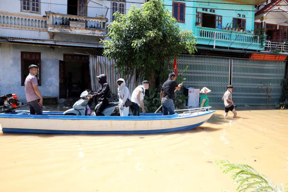Người dân xã Thất Khê (Lạng Sơn) di chuyển bằng thuyền qua khu ngập sâu trên Quốc lộ 4A. (Ảnh: Văn Đạt/TTXVN)
