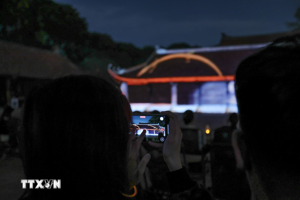 Du khách sử dụng điện thoại ghi lại buổi trình chiếu 3D mapping nghệ thuật. (Ảnh: Phạm Tuấn Anh/TTXVN)