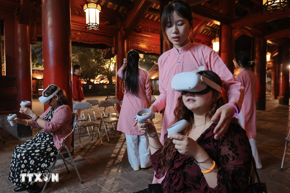Khách du lịch trải nghiệm viết thư pháp bằng kính thực tế ảo. (Ảnh: Phạm Tuấn Anh/TTXVN)