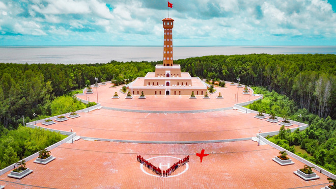 Đoàn Báo Điện tử VietnamPlus chào cờ tại vùng đất cực Nam Tổ quốc. (Ảnh: Hoài Nam/Vietnam+) VietnamPlus: Về Nguồn nơi ‘đất biết nở, rừng biết đi và biển sinh sôi' ảnh 1