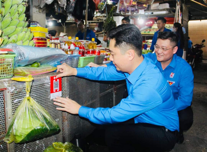 Thanh niên Nghệ An dán mã QR, số hóa hoạt động thanh toán tại các chợ. (Ảnh: PV/Vietnam+) Ấn tượng với các hoạt động chuyển đổi số trong Tháng Thanh niên ảnh 2