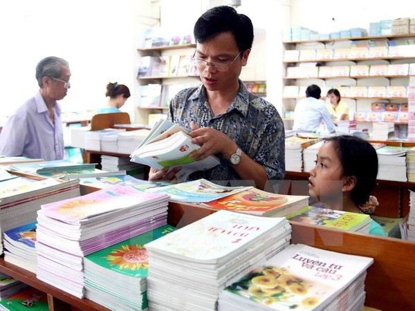 Phụ huynh và học sinh lựa chọn sách giáo khoa. (Ảnh: TTXVN) Chiều nay, Bộ Giáo dục chính thức công bố sách giáo khoa lớp 1 mới ảnh 1