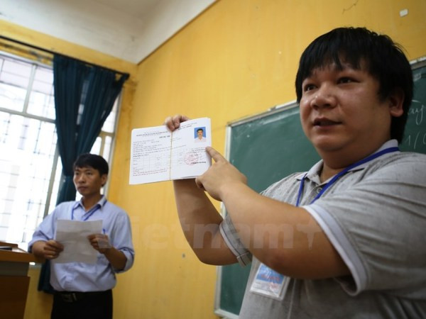 Cán bộ coi thi hướng dẫn thí sinh làm thủ tục dự thi trung học phổ thông quốc gia. (Ảnh: Lê Minh Sơn/Vietnam+) Thứ trưởng Bộ Giáo dục và Đào tạo “bật mí” về đề thi THPT quốc gia ảnh 2