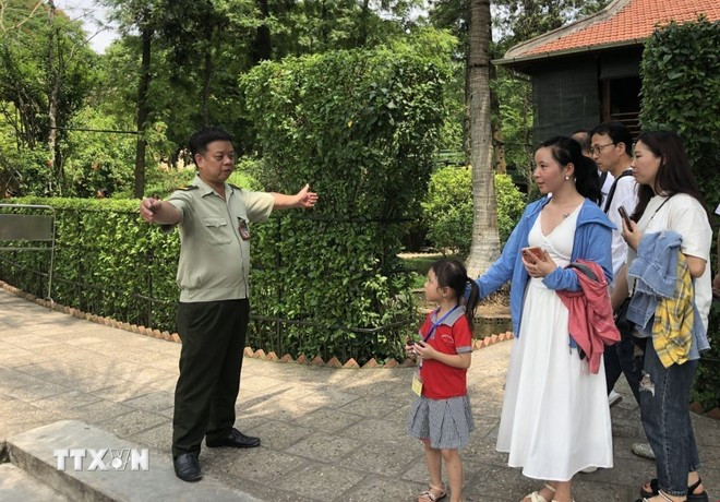 Nhân viên bảo vệ Khu Di tích Nhà sàn Bác Hồ hướng dẫn khách tham quan. (Ảnh: Phương Lan/TTXVN) ditich.jpg