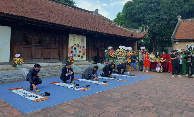 Các thư pháp gia trình diễn nghệ thuật viết chữ trên nền nhạc dân tộc. (Ảnh: Minh Thu/Vietnam+) vnp_thuphap3.jpg