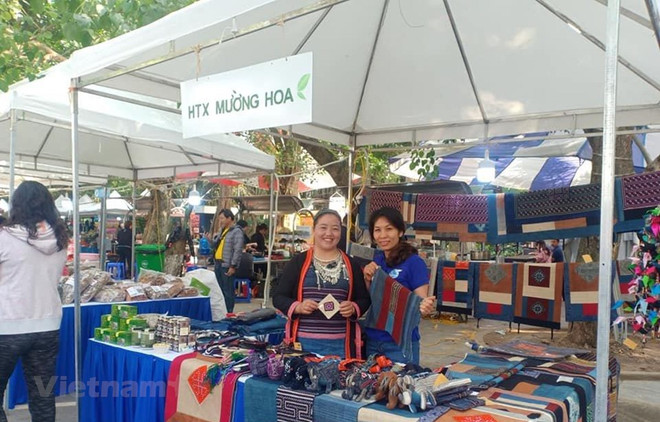 Chị Sùng Thị Lan (trái) quảng bá sản phẩm của hợp tác xã Mường Hoa ở hội chợ. (Ảnh: NVCC) Nữ giám đốc người Mông: Làm giàu từ nghề thổ cẩm truyền thống ảnh 1
