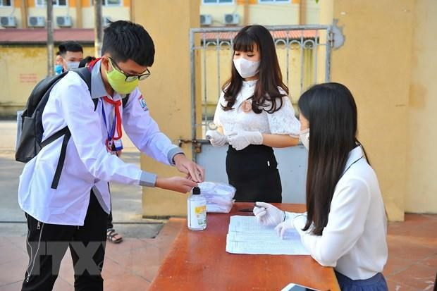Học sinh thực hiện sát khuẩn tay trước khi vào trường. (Ảnh: TTXVN) Dịch COVID-19 phức tạp, nhiều địa phương thay đổi kế hoạch năm học ảnh 1